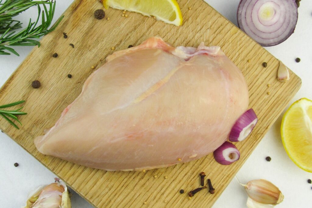 Raw chicken on a chopping board. Credit: Unsplash