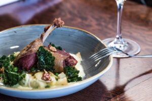 Crisp duck confit with side garnish.