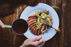 Duck confit with sauce being poured on. Credit: Unsplash