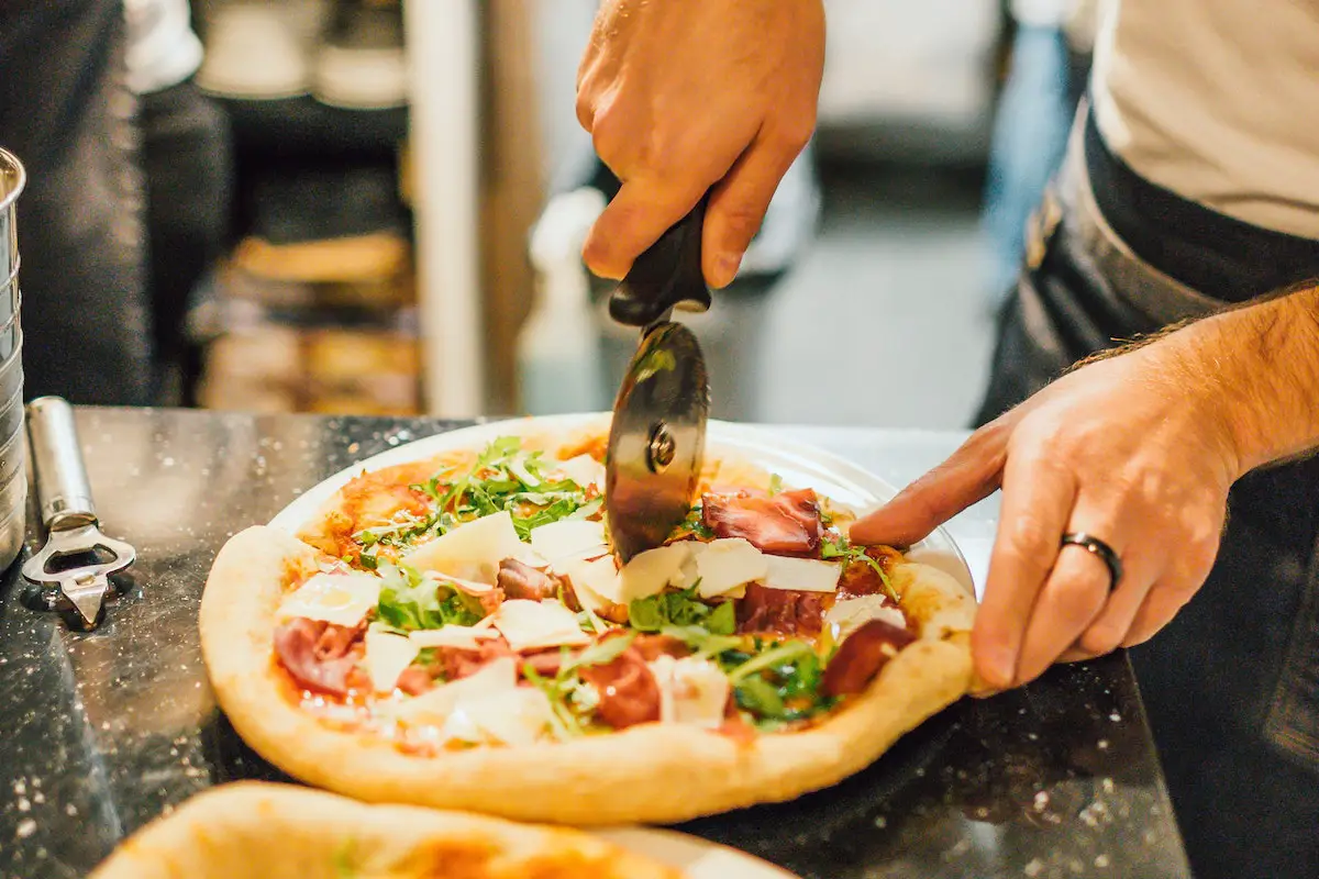Cutting pizza with a traditional pizza wheel. Credit: Unsplash