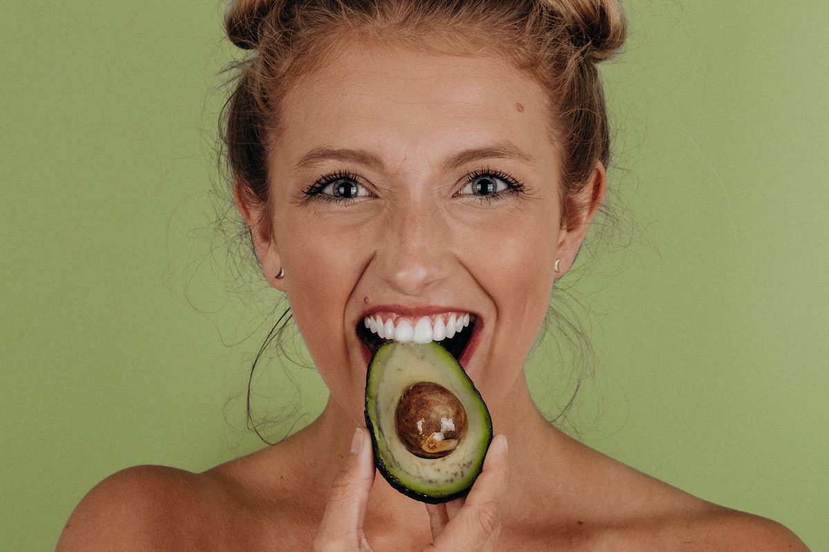 Girl eating an avocado with the skin still on. Credit: Unsplash/Noah Buscher