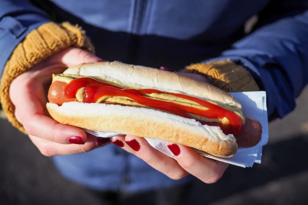 Holding a cooked hot dog.