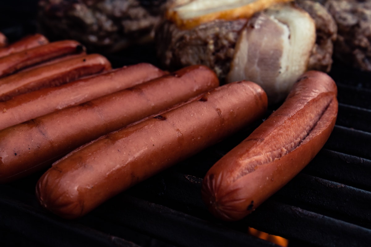 Hot dogs cooking on a grill.
