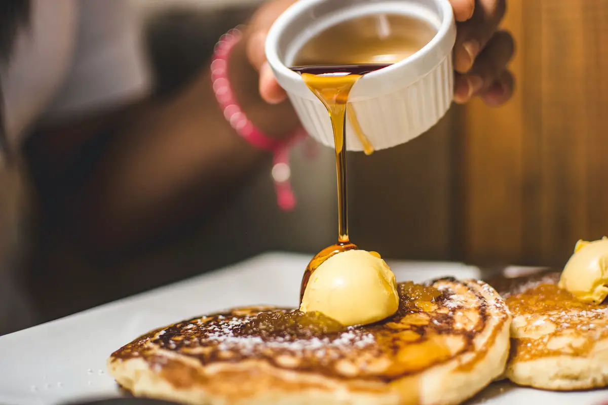 Maple syrup being poured over butter on pancakes. Credit: Unsplash