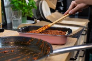 Lasagna bolognese being put into a dish. Credit: Unsplash